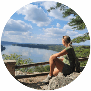 young women sitting on rock looking at river view