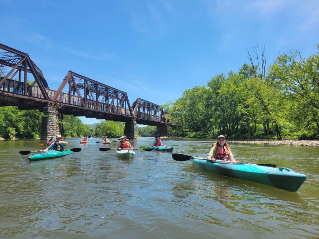 kayakers on a river with railroad bridge