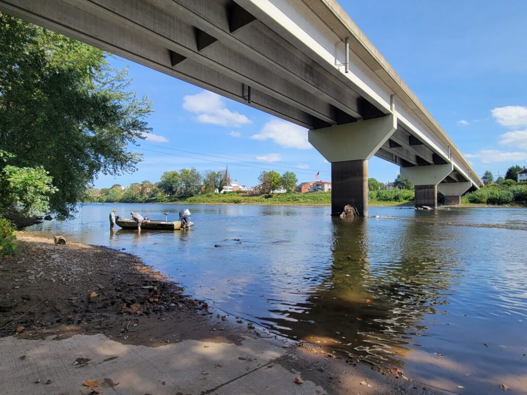 boat launch and boaters under a bridge