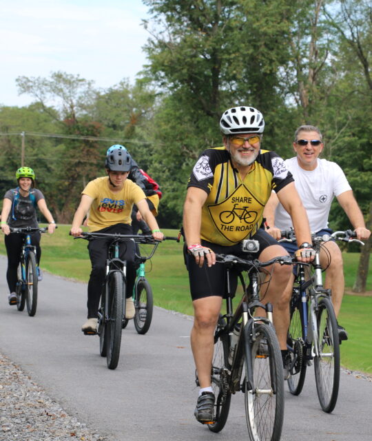 Cyclists travel along a gravel path.
